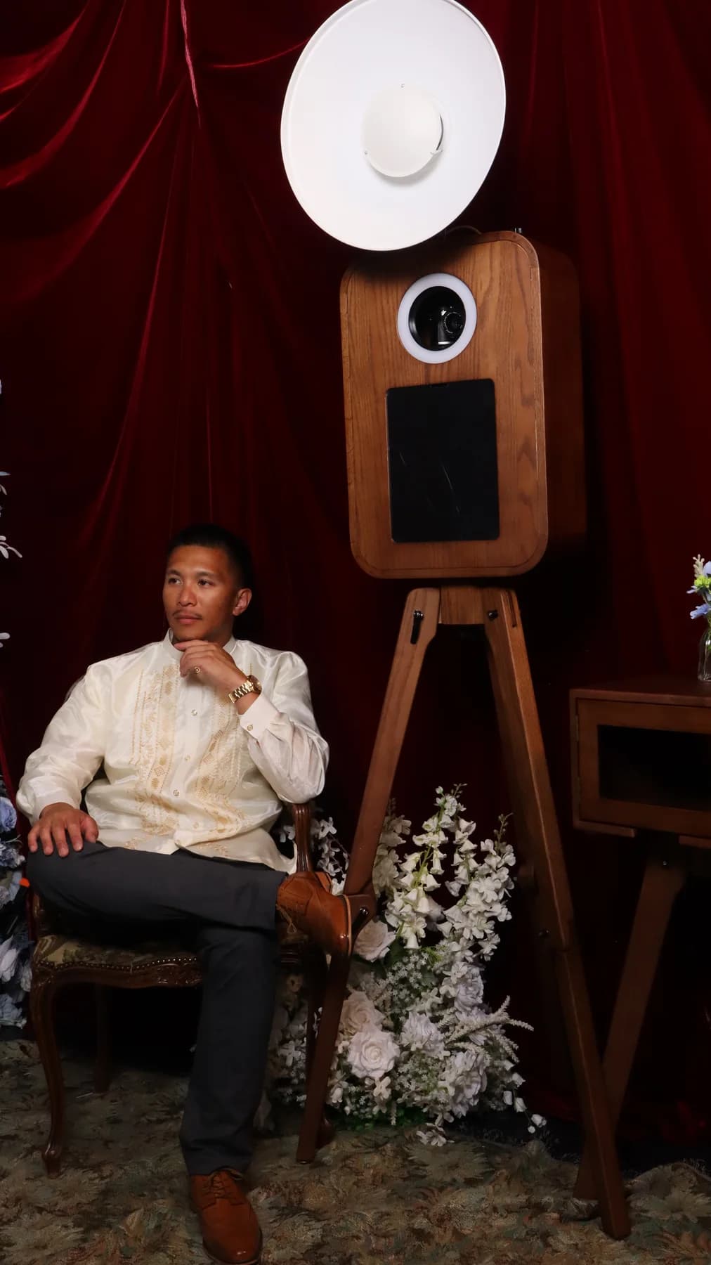 One Katha founder seated beside the oak booth against a deep-red drape